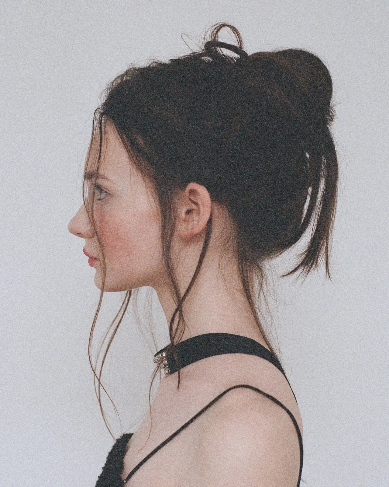 Side-profile portrait of Ellie with her hair pinned up and loose strands framing her face