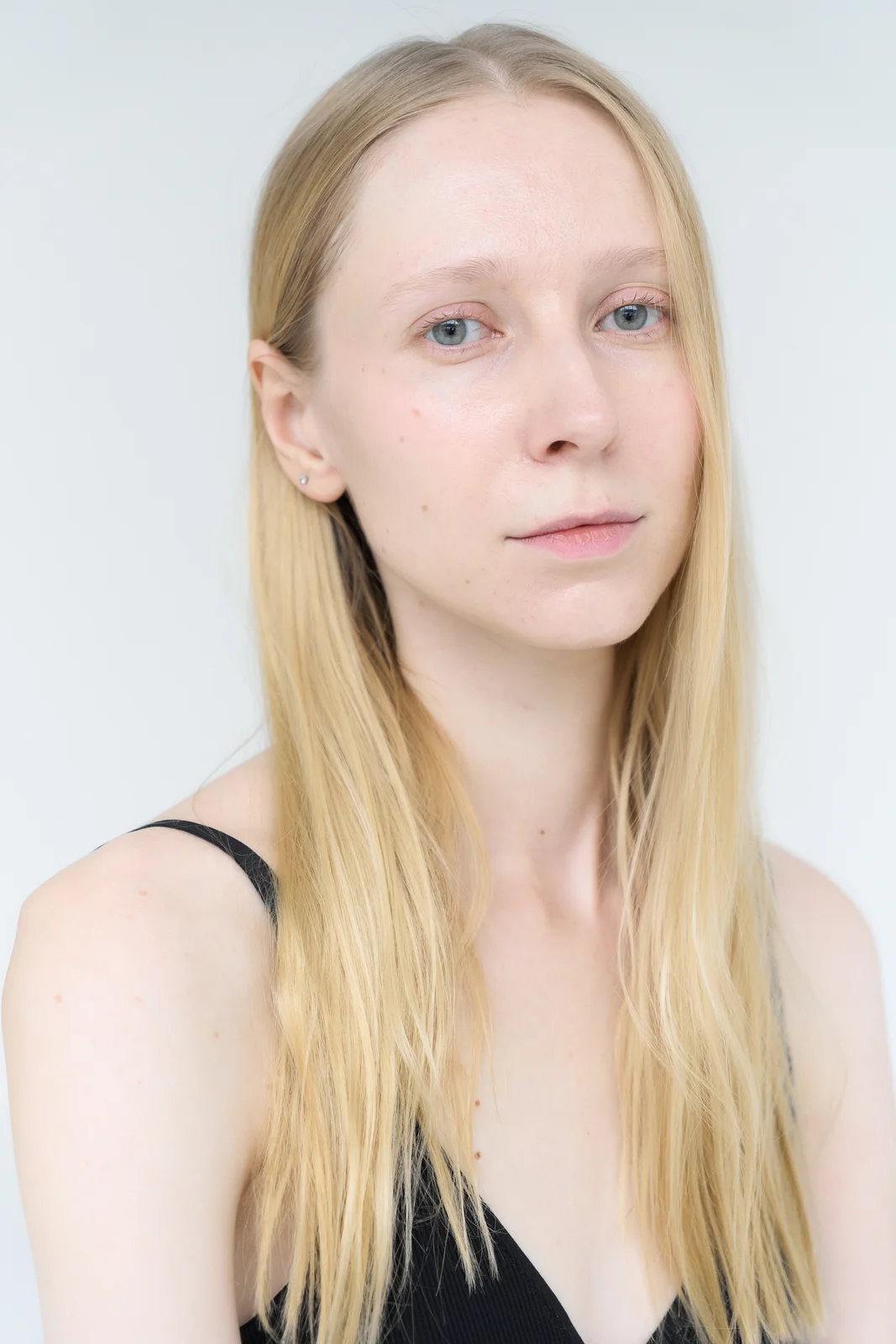 Head-and-shoulders portrait showing dropped shoulders and a long neck, the head slightly tilted