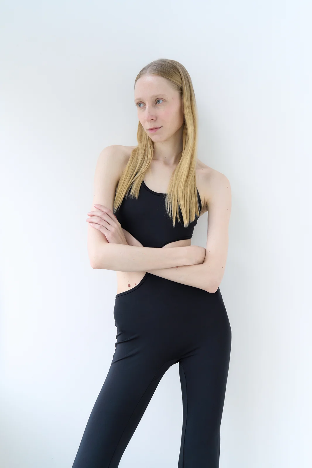 Model with her arms loosely crossed and her head turned to the side in a relaxed, candid moment