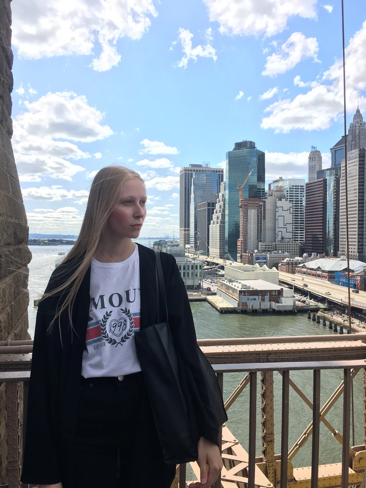 Model in a blazer looking out over the Lower Manhattan skyline from the Brooklyn Bridge